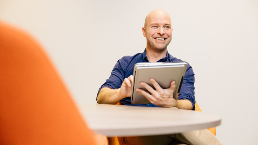 Man met ipad in handen glimlacht