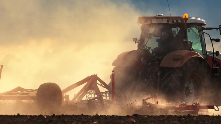 Tractor met aanhanger rijdend creeërt stofwolk
